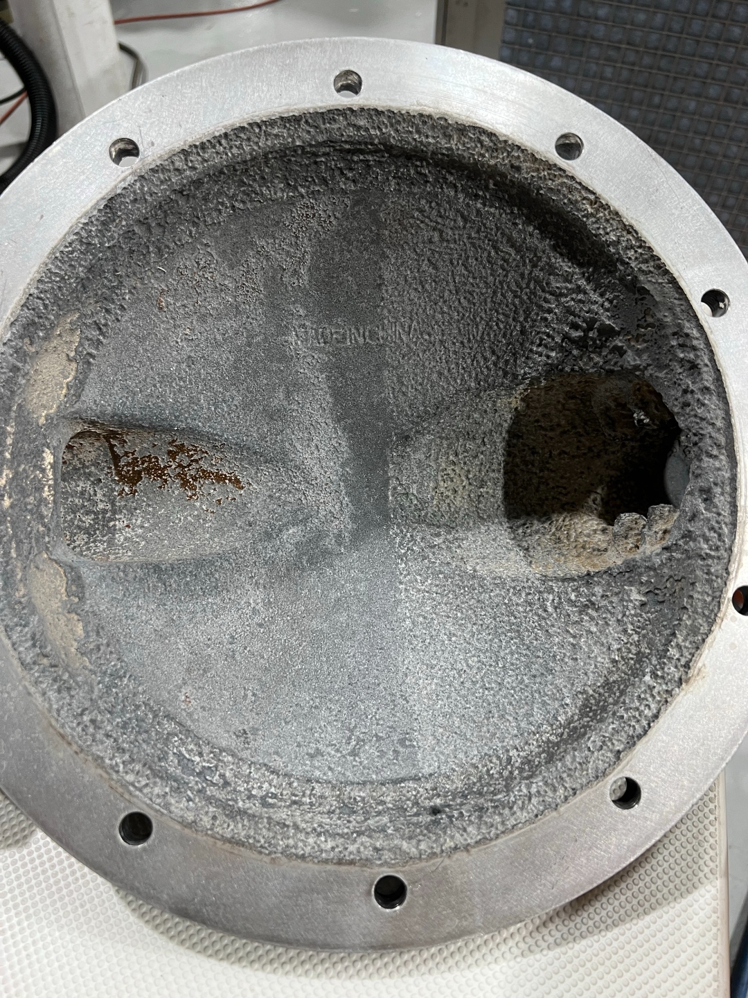Aluminum pump housing before AEGIS coating, showing heavy white-gray corrosion scale and pitting inside the bore