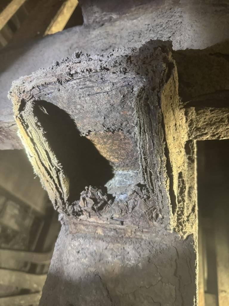 Steel mill structural framework with traditional coating after six months acidic exposure showing complete coating failure