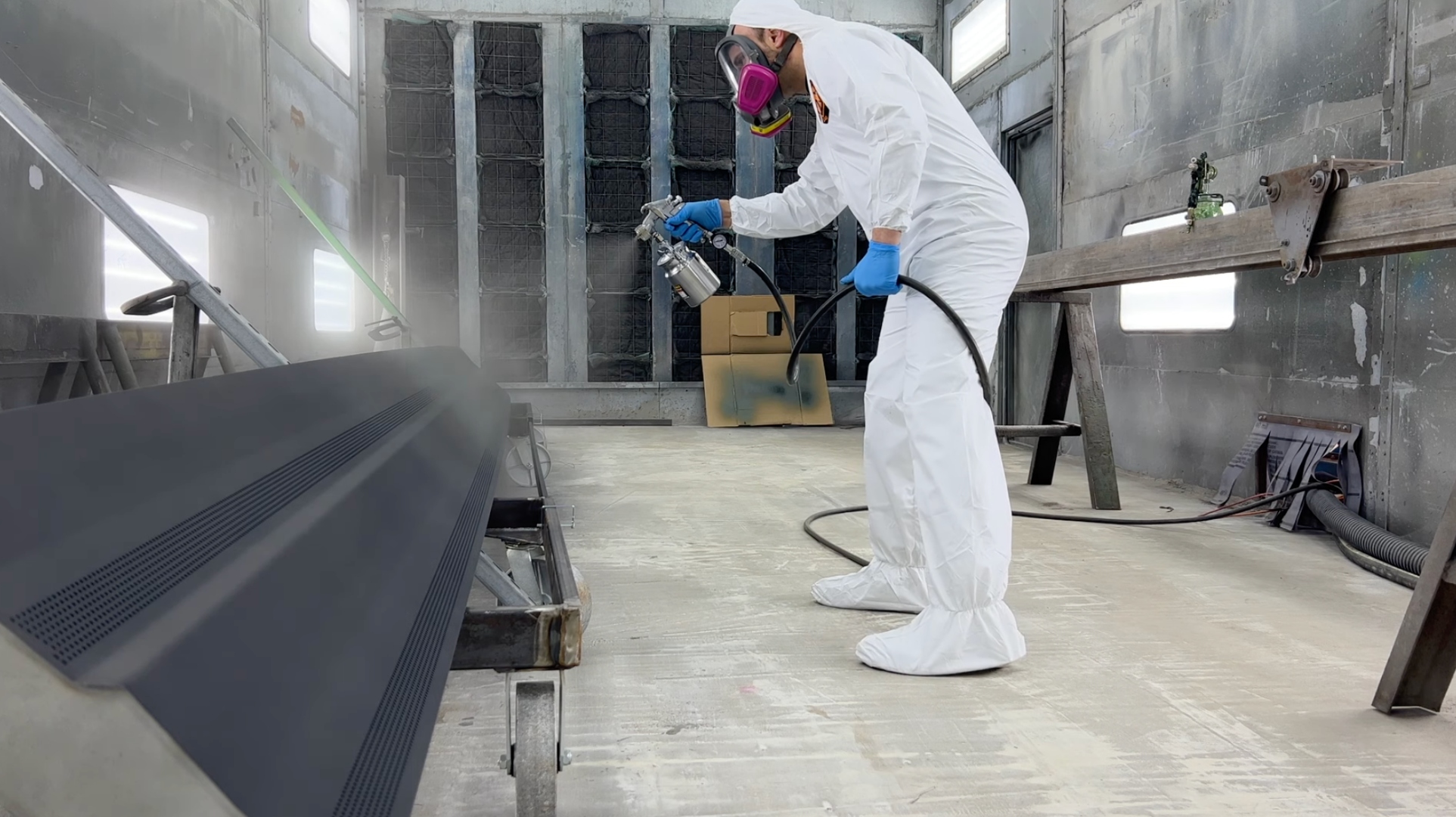 AEGIS technician applying fluoropolymer coating to a long industrial diffuser in the Elkton, Maryland spray booth